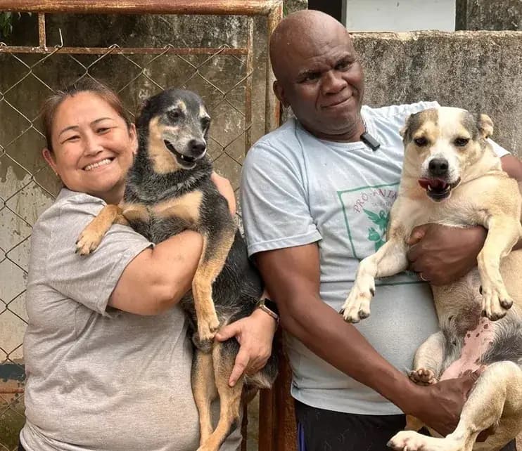 Casal do Siulsan Resgate segurando no colo dois cães resgatados, em frente ao canil do abrigo em Tatuí.