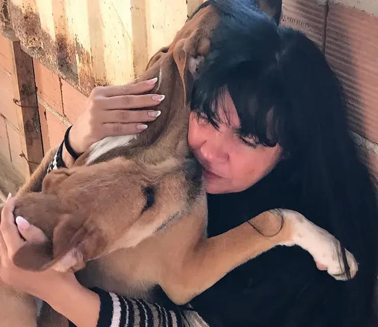 Voluntária da SOS Joana Darc abraçando um cão resgatado dentro do abrigo em Santa Luzia.