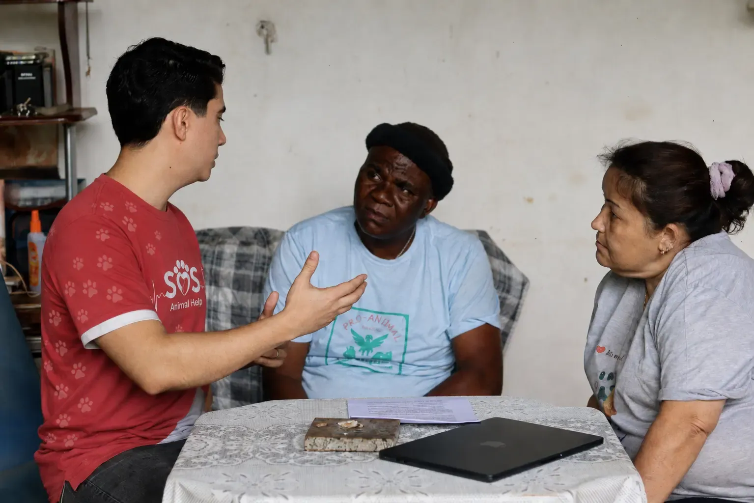 An SOS Animal Help volunteer explaining the terms of the partnership to two rescuers seated at a table.
